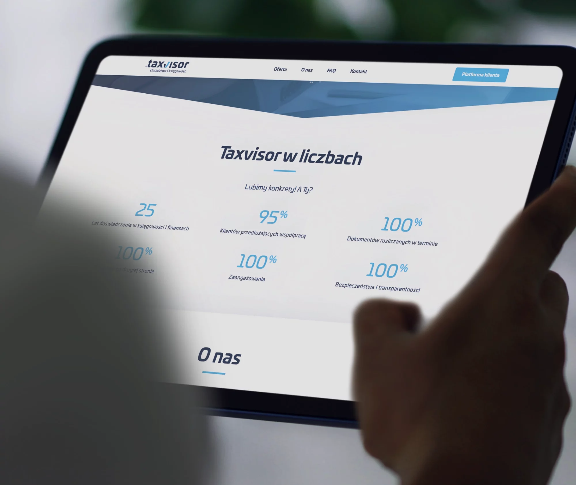 Tablet trzymany w dłoniach z widokiem strony Taxvisor i sekcji „Taxvisor w liczbach”.