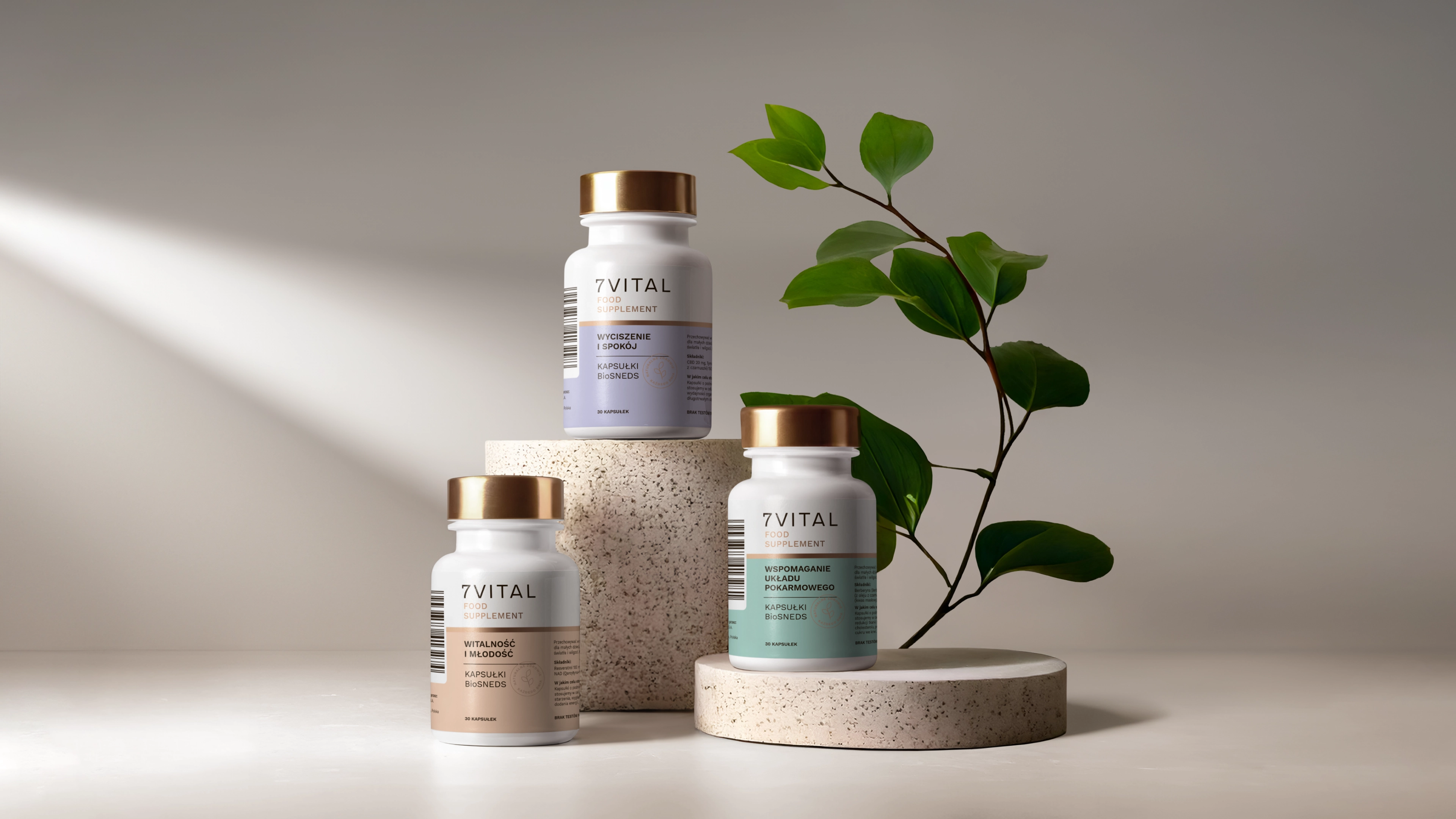 Trzy butelki naturalnych suplementów 7Vital ustawione na kamiennych podstawkach z zieloną gałązką w tle