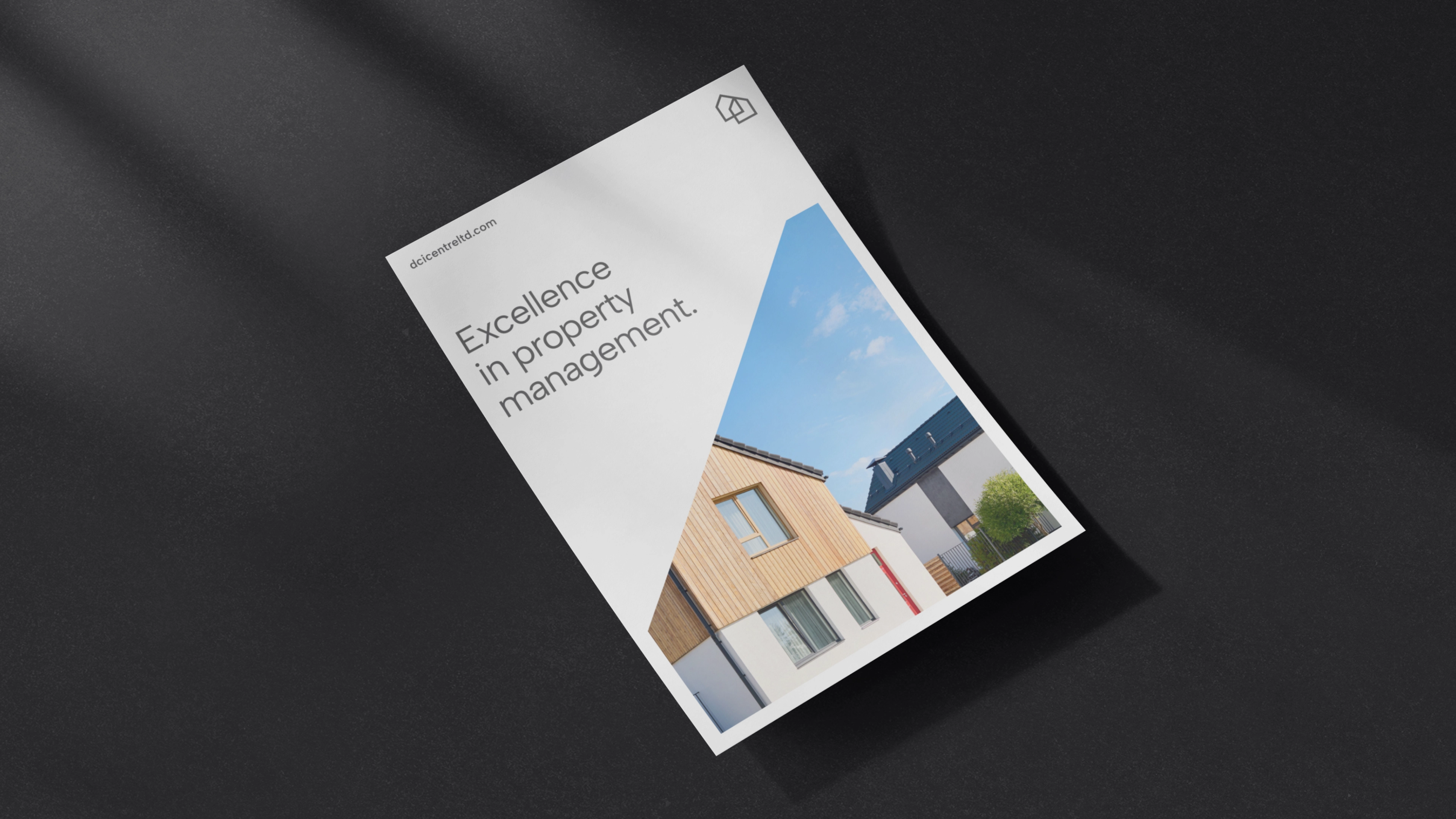 Folder reklamowy operatora nieruchomości DCI Centre w białej oprawie z geometrycznym wycięciem ukazującym zdjęcie nowoczesnych budynków, leżący na ciemnym tle