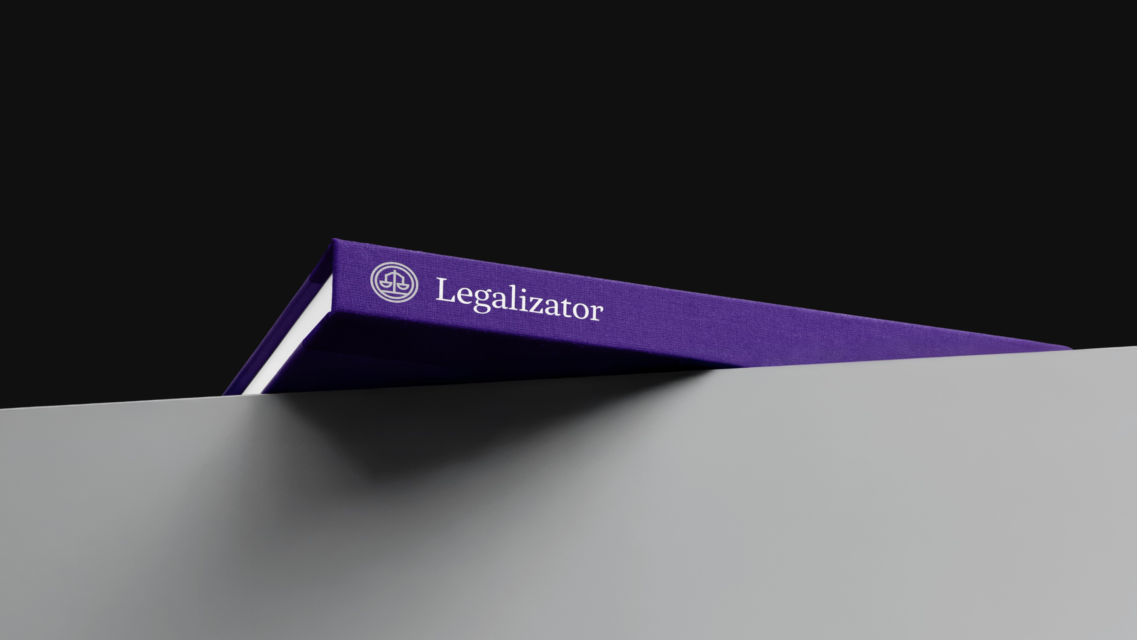 Grzbiet fioletowej teczki z logo Legalizator widoczny na krawędzi biurka na ciemnym tl