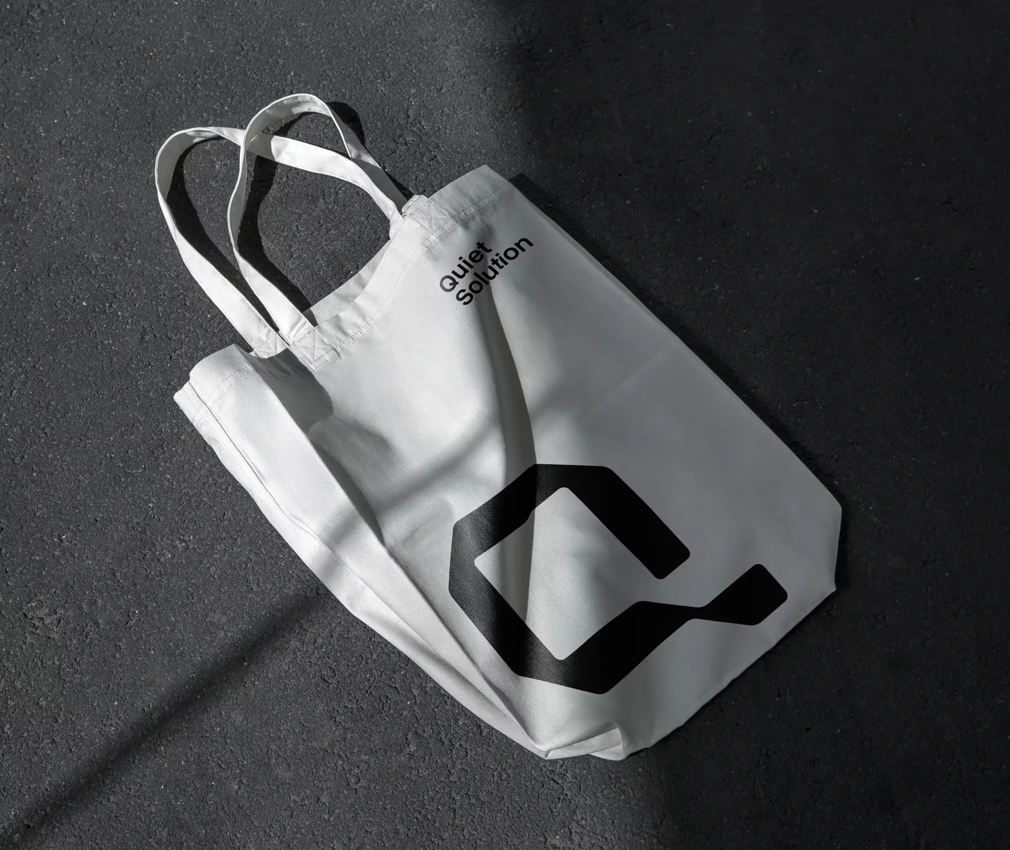 Torba bawełniana Quiet Solution z czarnym logo na jasnym tle w minimalistycznej identyfikacji wizualnej.